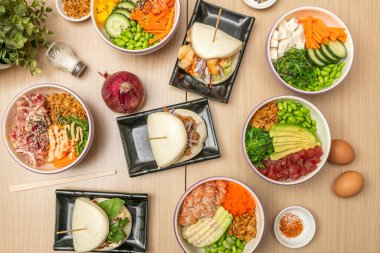 Çeşitli balık kaseleri, tofu, sebze, bao ekmeği ve baharatlar.