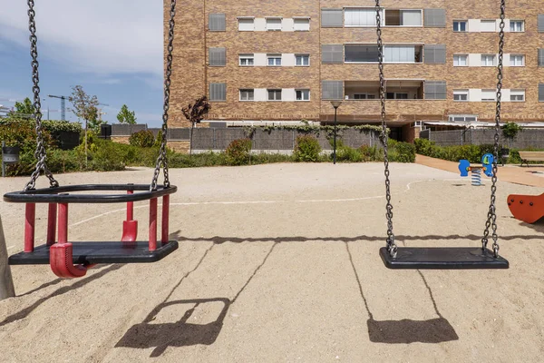 Common areas of a building with a sand esplanade, some games for children, some swings