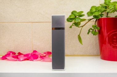 Süslü bitkilerle birlikte beyaz bir rafta karton bir kap.