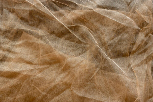 A background of semi-transparent brown tulle fabric with some wrinkles