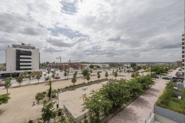 Bahçeleri ve oyun alanları olan inşaat halindeki binalarla dolu büyük bir cadde.