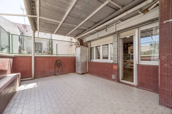 stock image Courtyard of a house with a white tile floor and red tiles on the walls and a house door made of white aluminum and glass