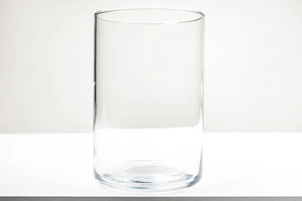 白い木製のテーブルの上に蓋のない大きな空のガラス瓶 — ストック写真