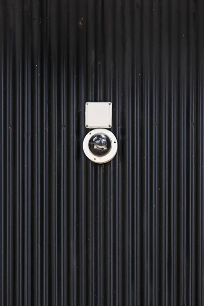 安装在波纹黑色金属墙上的监控摄像头 — 图库照片