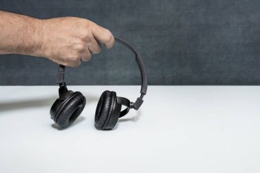 Siyah kablosuz kulaklığı tutan bir el.