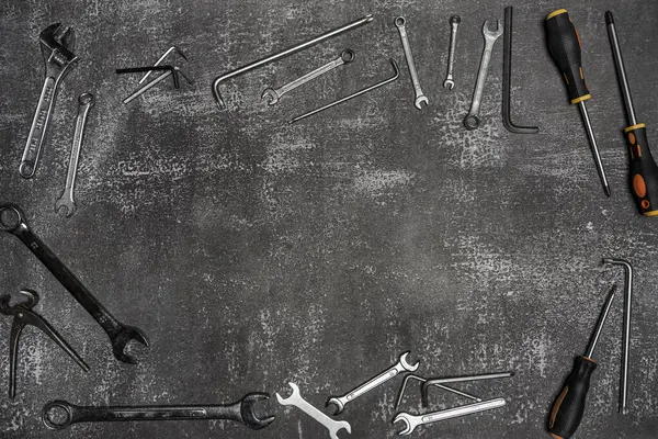 open-end wrenches, phillips screwdrivers, tape, hammers and other simple tools on a grated gray background