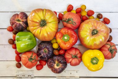 Her çeşit domatesin tepesinde yaşam görülür. Menteşeli ahşap bir yüzey üzerinde biber.