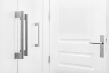 Desenli metal, beyaz, ahşap dolap kapılarını içeri çeker.