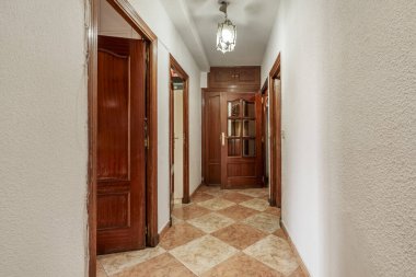 Verniklenmiş ahşap odalara giriş kapısı olan bir evin dağıtım koridoru.