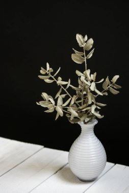 Kurumuş dekoratif kalp dalları olan küçük beyaz cam bir kavanoz.