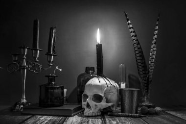 Şamdandaki mumların siyah ve beyaz bir görüntüsü, katipler için balmumu damlaları ve klasik nesnelerle dolu bir kafatası.