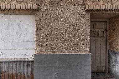 Boya soyan eski bir binanın duvarı, terk edilmiş kapılar ve pencereler..