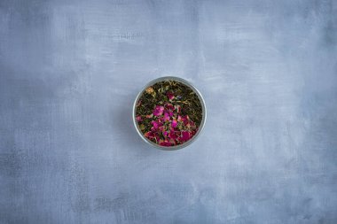 Kurutulmuş çay yaprakları ve kurutulmuş gül çayıyla dolu metal bir kavanoz. 