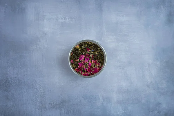 Kurutulmuş çay yaprakları ve kurutulmuş gül çayıyla dolu metal bir kavanoz. 