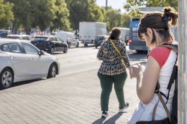 İnsanlar sokakta yürürken, cep telefonlarıyla oynuyorlar.