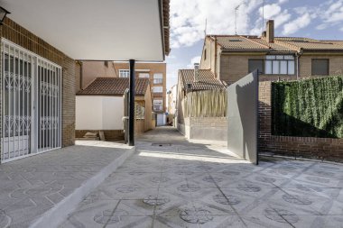 Terrazzo zemini olan tek bir aile evinin verandası, koyu kahverengi beton tuğlalarla inşa edilmiş bir bina ve hatta siyah metal bir kapı.