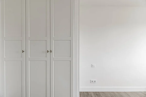 Empty room with fitted wardrobes with white wooden doors