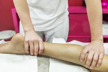 Hastanın bacağına baskı uygulayan bir masöz.