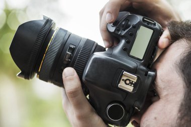 Bir fotoğrafçı fotoğraf çekmek için kamerasının görüş açısına bakıyor.