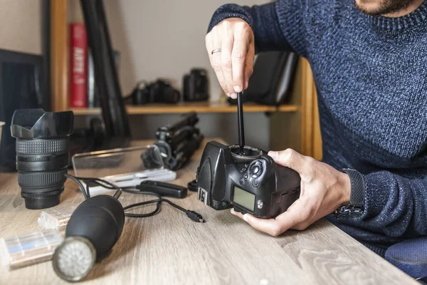 A photographer cleaning the image sensor of his equipment on an office table