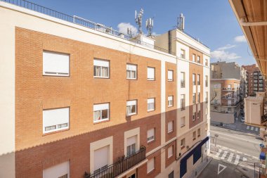 Çatıda birkaç cep telefonu anteni olan bir apartmanın ön cephesinde pencereler