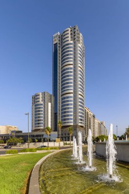 Metal ve camlı kıvrımlı cepheli otel ve ofisleri olan yüksek bir bina.