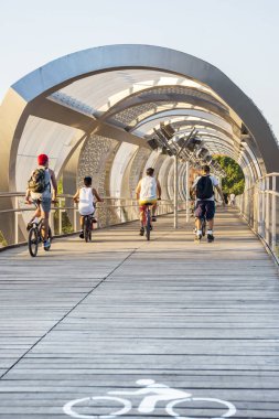 Bazı biniciler bisikletleriyle Madrid 'deki Manzanares nehrinin üzerinden geçiyorlar.