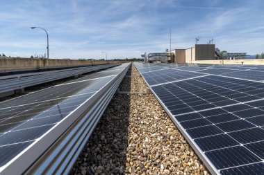 Açık bir günde çakıllı bir binanın çatısına modern güneş panelleri kurulmuş.