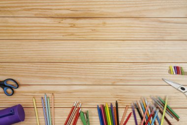 Renkli kalemlerle dolu sakin bir hayat, bir grup kalem, makas ve ahşap bir masada bir tuvalet çantası.