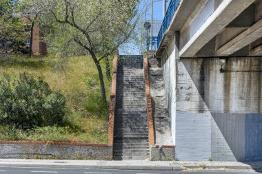 Granit basamaklı bir merdiven, bir tarafında köprü duvarı ve diğer tarafında bahçe alanı olan bir merdiven.