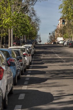 Arka planda Madrid telekomünikasyon kulesi ve yeşil ışığı olan park halindeki arabaların yanındaki yarışa bakın.