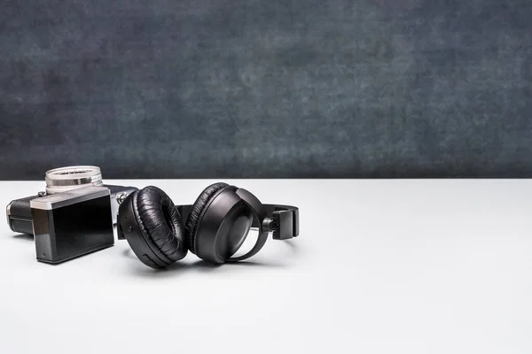 black over-ear headphones next to a vintage camera with flash
