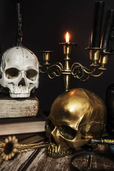 An image of candles in a candlestick, some skull with drops of cere, another gold and a burning candle