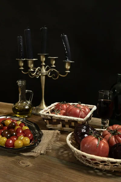 Still life with tomatoes of various kinds with a little olive oil in various trays on an untreated wooden surface