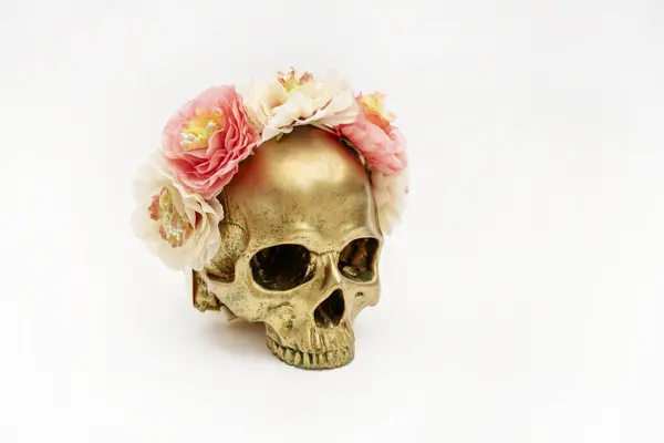 A very cute golden skull with its flower headband on a plain white background