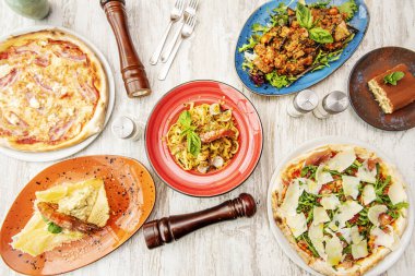 Bir sürü makarna, parmesan peyniri ve çeşit çeşit pizzayla İtalyan yemek takımı.