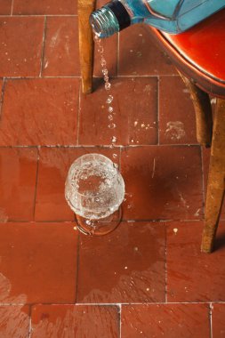 Mavi bir şişeden şeffaf sıvı alan cam bir kadeh.