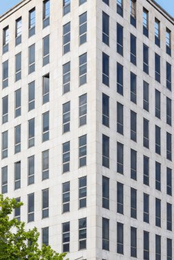 Mermer kiremitleri ve birçok benzer penceresi olan bir ofis binasının ön cephesi