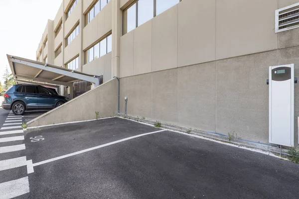 An uncovered parking space with a fast charger for electric vehicles in an office building