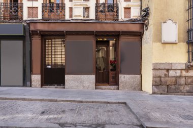 Sokak seviyesindeki eski bir binada, kahverengi ahşap cepheli ve granit bloklu bir ticari bina.