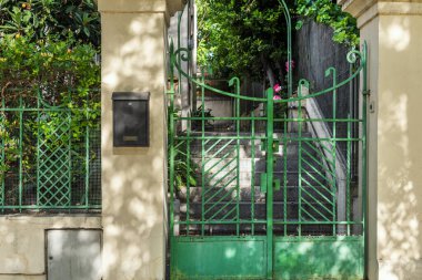 Metal çitli, yeşil ve gri granit merdivenli tek kişilik bir evin kapısı.