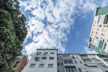 Gökte beyaz bulutlar ve bahçeli apartman binalarının alçak açılı görüntüsü