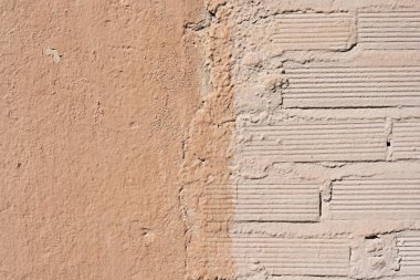 Hafif koyu renkli pürüzsüz bir duvarın yanına açık renge boyanmış ucuz bir tuğla duvar.