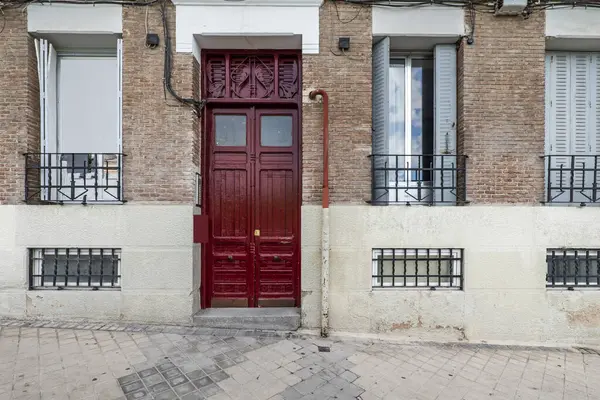 Red wooden access door to a portal of urban residential homes