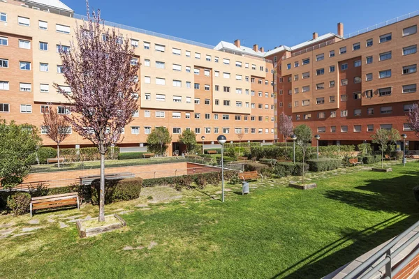 Garden common areas with young woodland, condominium wooden seats on a sunny day