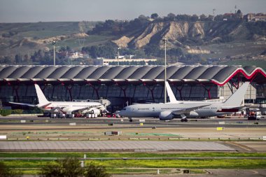 Madrid Barajas havaalanı terminallerinden birinin yanındaki pistlerden geçen uçaklar.