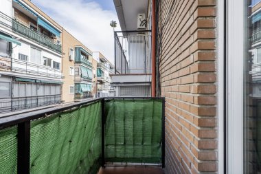Siyah metal korkuluklu, mat yeşil kumaşlı küçük bir apartman dairesi.