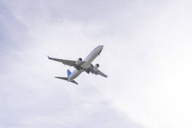 Bulutlu bir günde havaalanı pistine yaklaşan bir yolcu uçağının gövdesinin görüntüsü.
