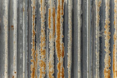 Paslı kıvrımlı metalle kaplı bir duvar.