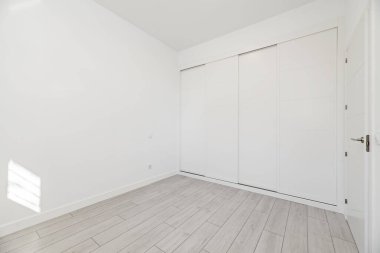 İçinde beyaz sürgülü kapılar ve beyaz ahşap marangozlar olan boş bir oda.